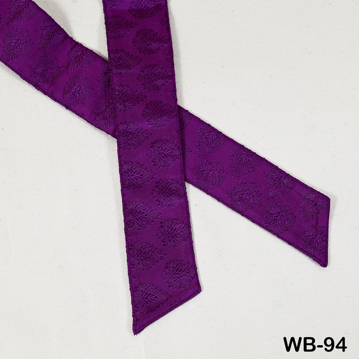a purple fabric with a repeating leaf pattern, lying on a white surface.