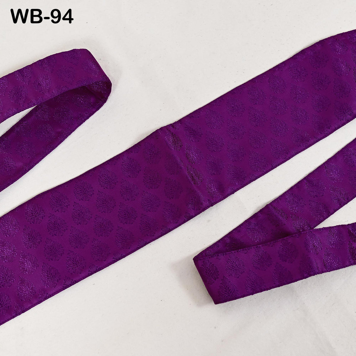 a purple fabric with a repeating pattern of small circles or dots, laid out on a white surface.
