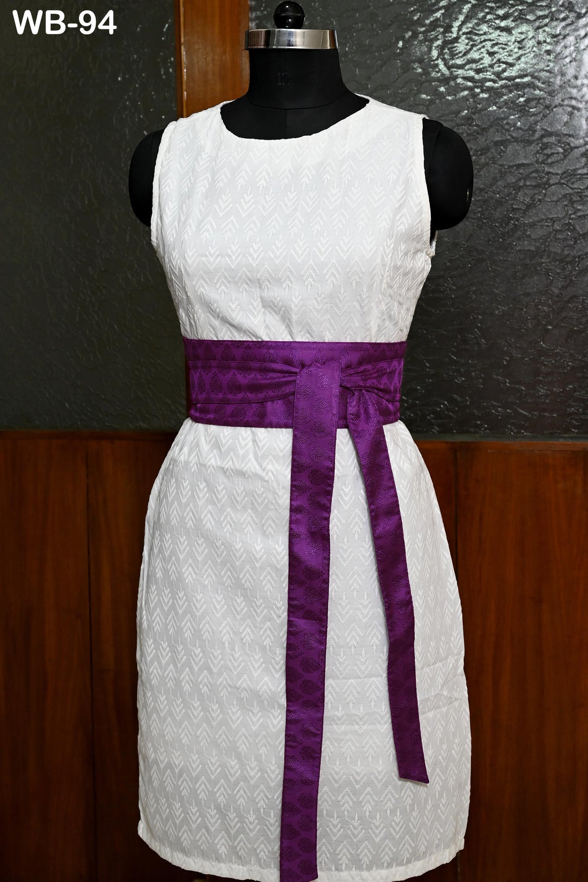 A white dress with a purple sash, displayed on a mannequin.