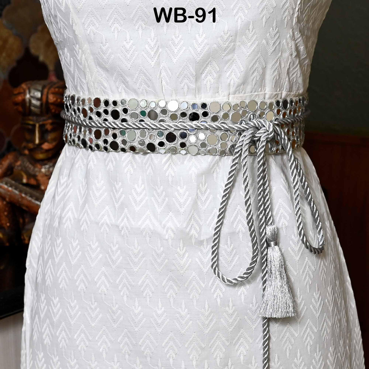 A white dress with a silver belt featuring a tassel.