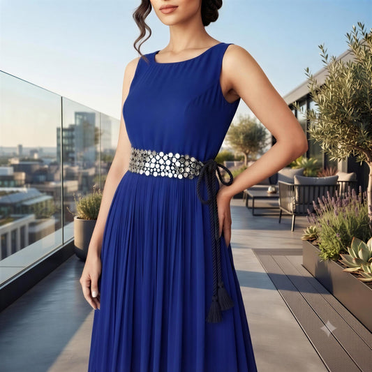 A woman wearing a blue dress with a silver belt stands on a balcony overlooking a cityscape.