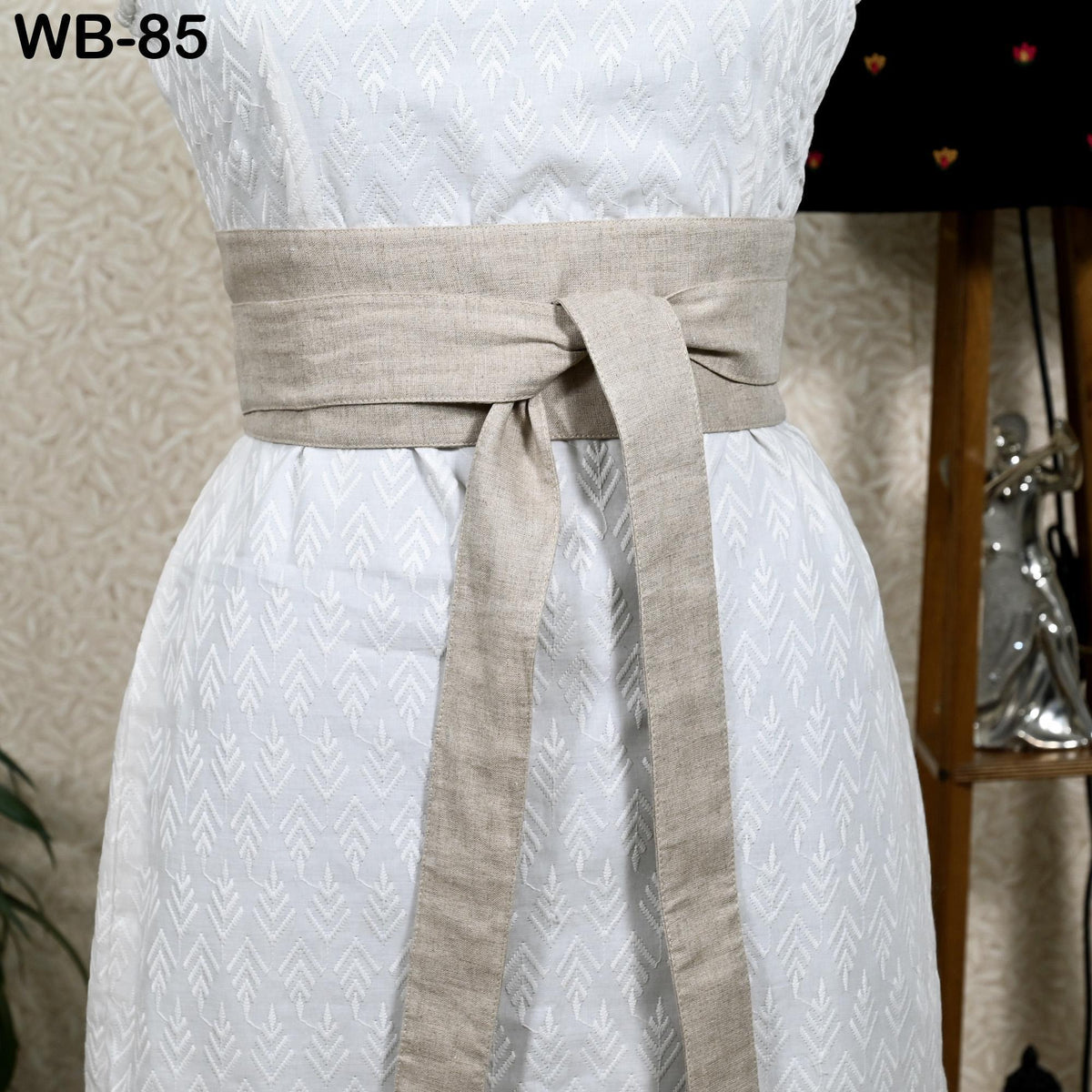 A white dress with a beige belt, displayed on a mannequin.