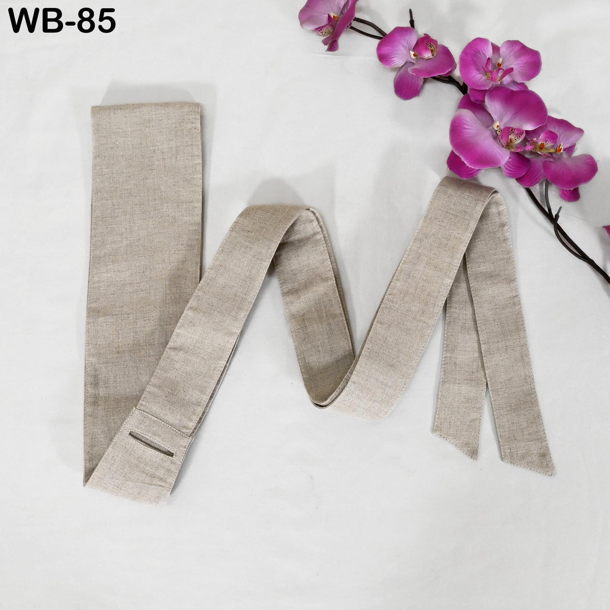 a beige tie with a floral arrangement of pink orchids placed next to it on a white background.