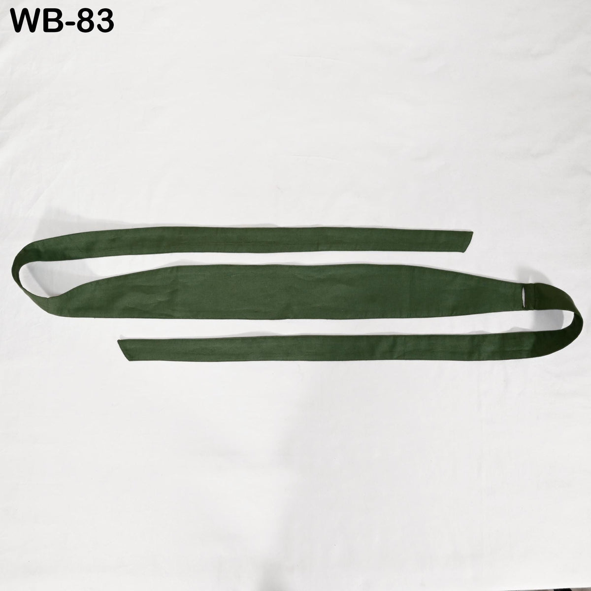 a green band or belt lying on a white surface.