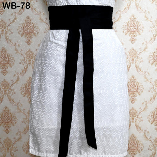 A white dress with a black belt, displayed against a patterned wallpaper background.