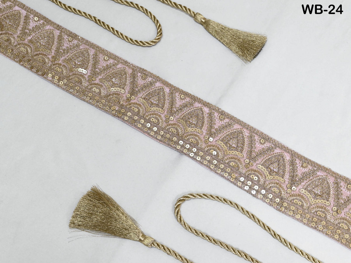 a decorative fabric with a pink and gold pattern, featuring a tassel and a rope.
