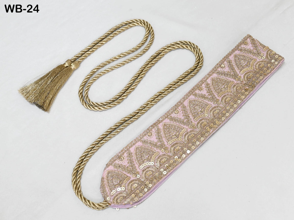 a decorative pink and gold belt with a tassel, placed on a white surface.