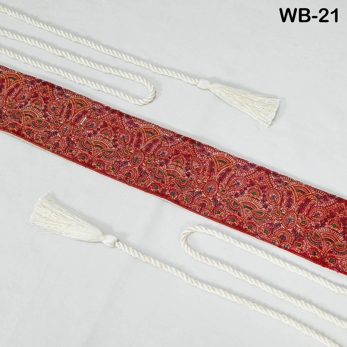 a decorative red and white paisley pattern on a white background, with two white tassles attached to the ends of the fabric.