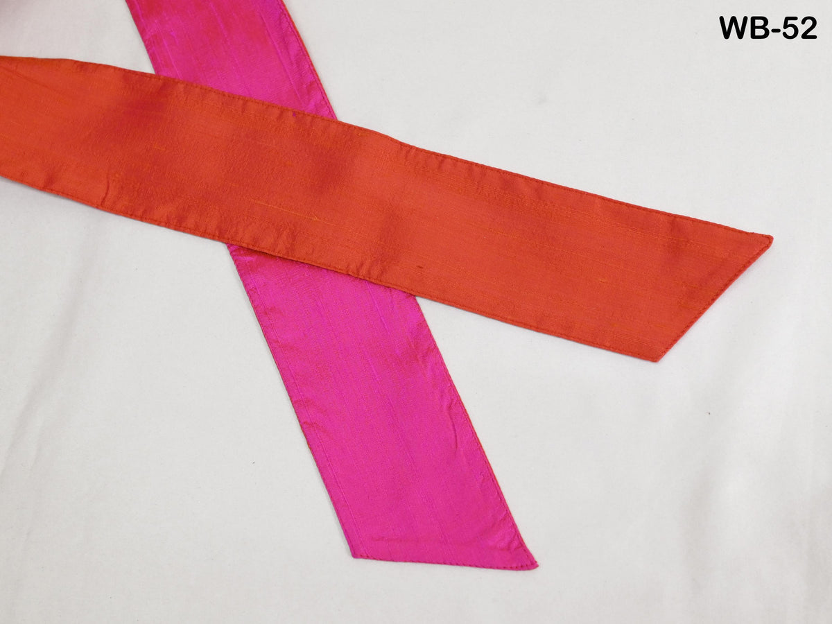 a close-up view of two colorful fabric strips, one red and one pink, lying on a white surface.