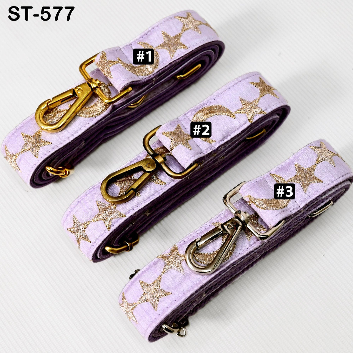 Three purple star-patterned straps with gold metallic buckles, each with a different number printed on it.