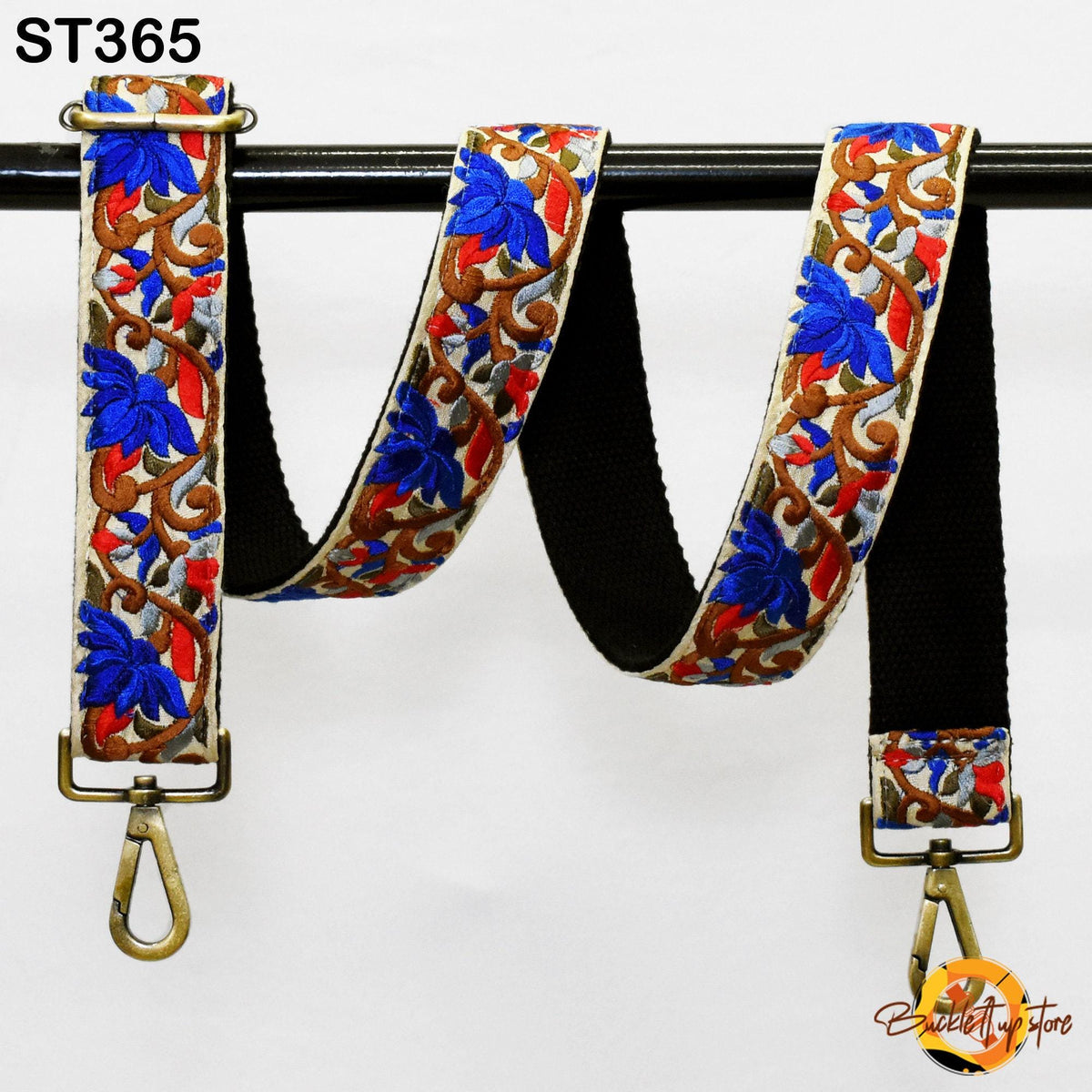 A colorful strap with a floral pattern, featuring blue and red flowers, is hanging on a black rod.