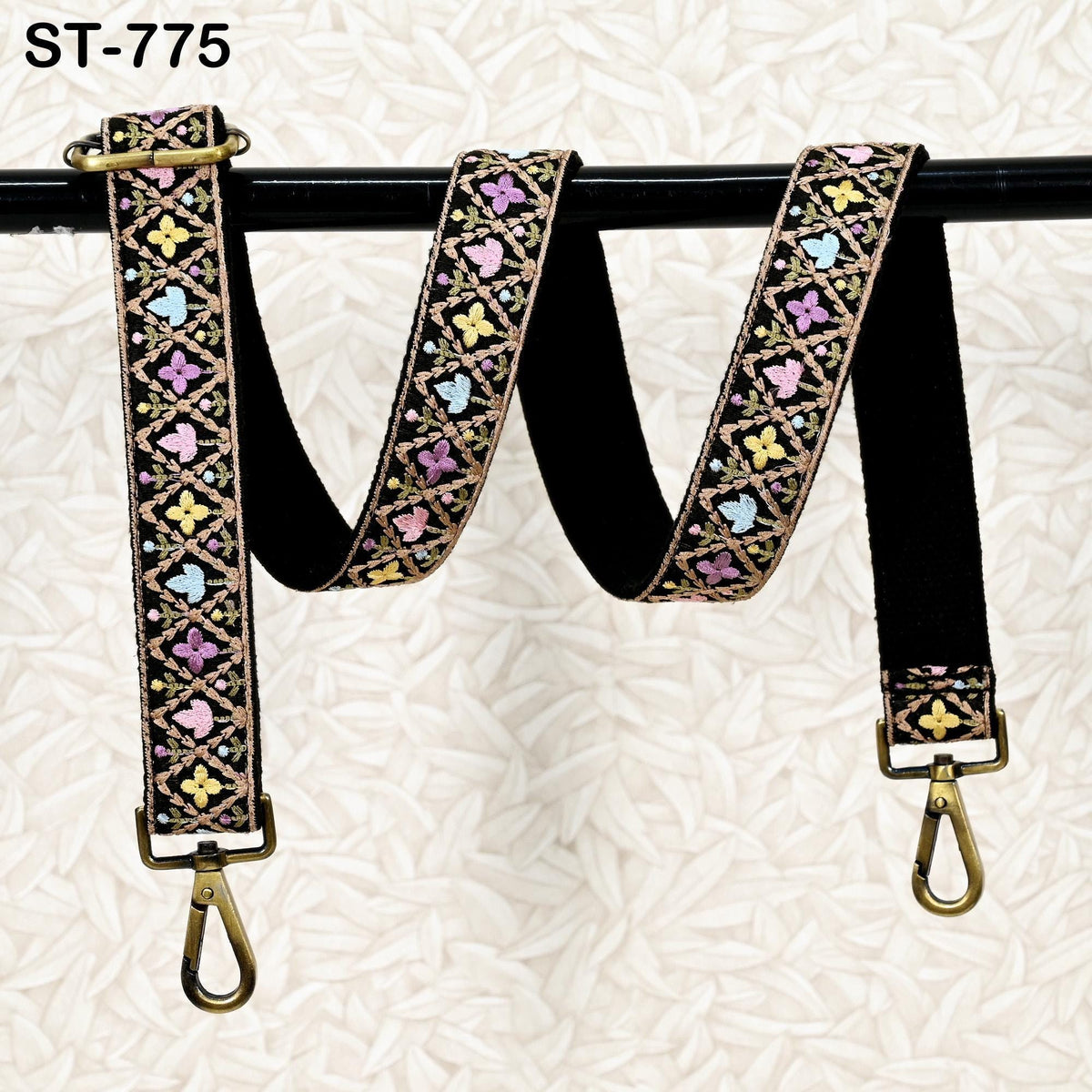 A colorful, patterned strap with a floral design, hanging from a black metal hook.