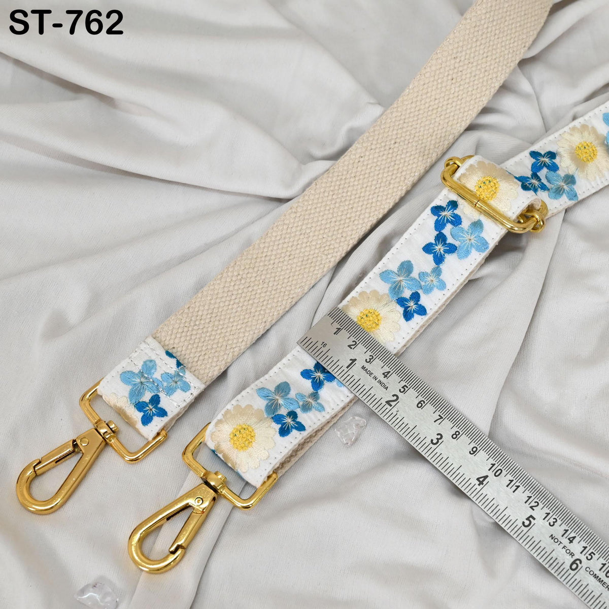 a beige strap with blue and white floral embroidery, and a ruler placed next to it, indicating the strap's length.