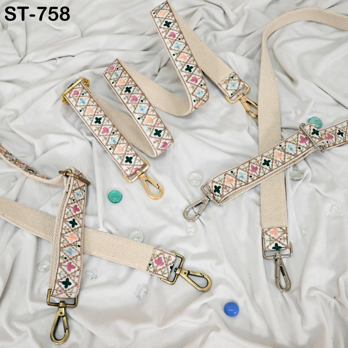 a collection of beige and white patterned straps with metal buckles, arranged on a white fabric background.