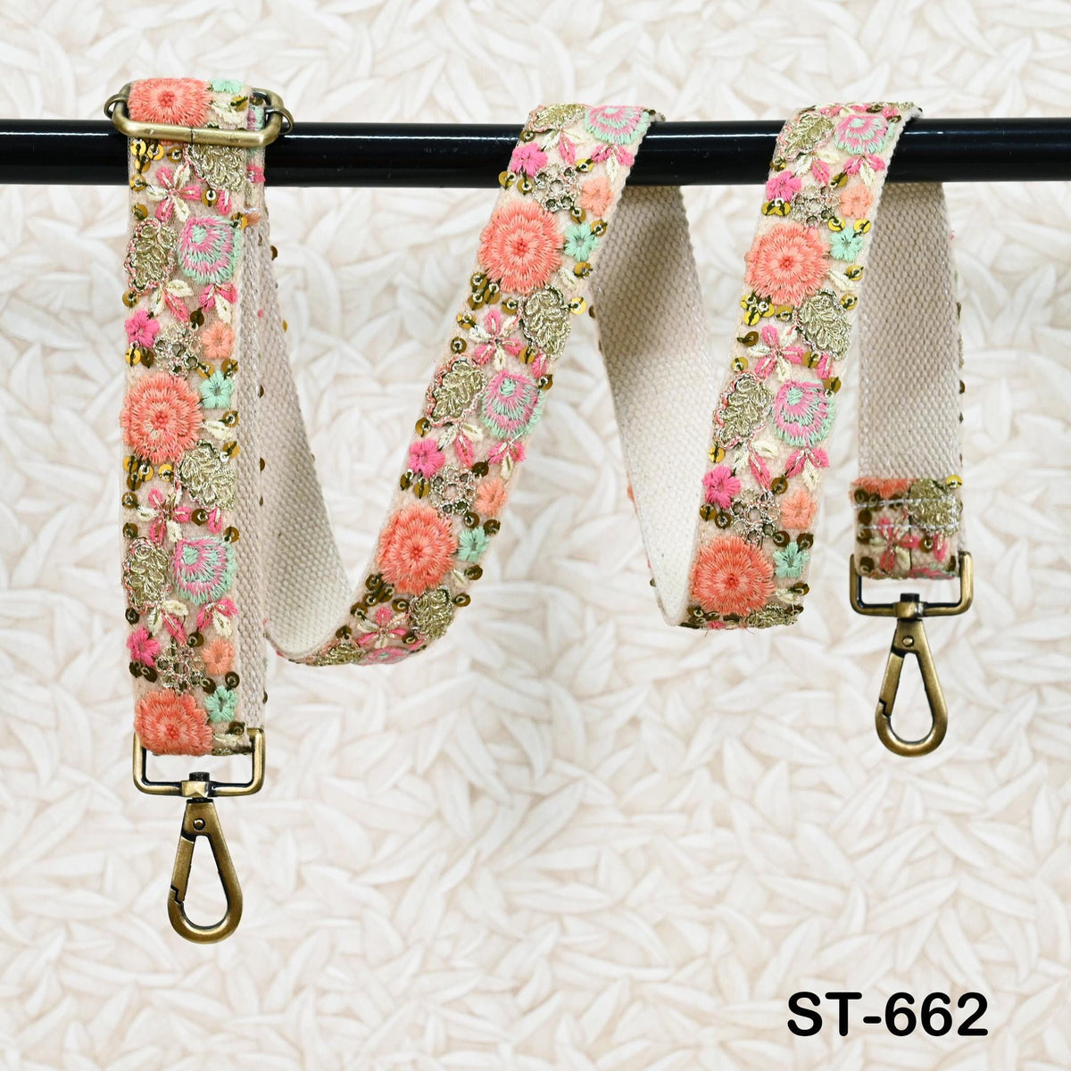 A floral-patterned strap with a metal clasp and hook attached to a black metal bar.