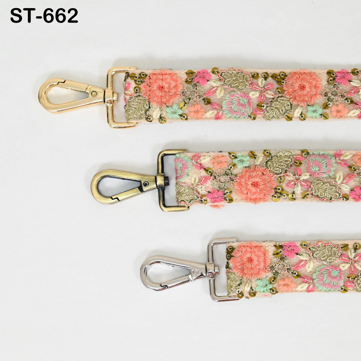 three straps with floral embroidery, each with a metal clasp and hook. The straps appear to be made of a light-colored material, possibly beige or white, with a floral pattern in shades of pink, green, and gold.