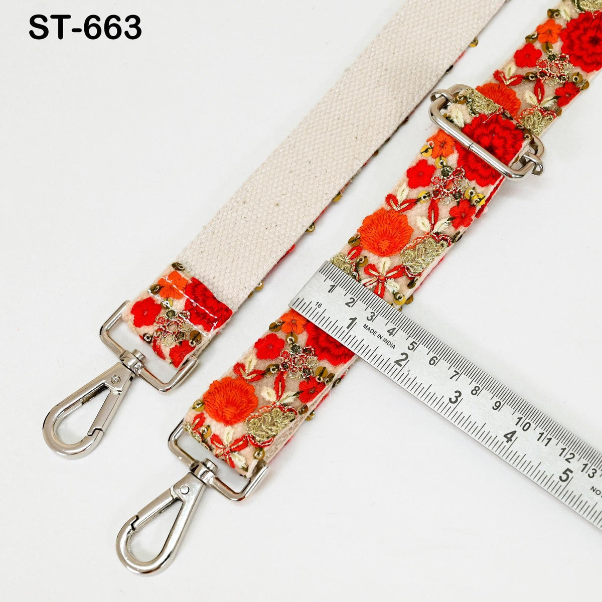 a floral-patterned strap with metal hooks and a ruler placed next to it.