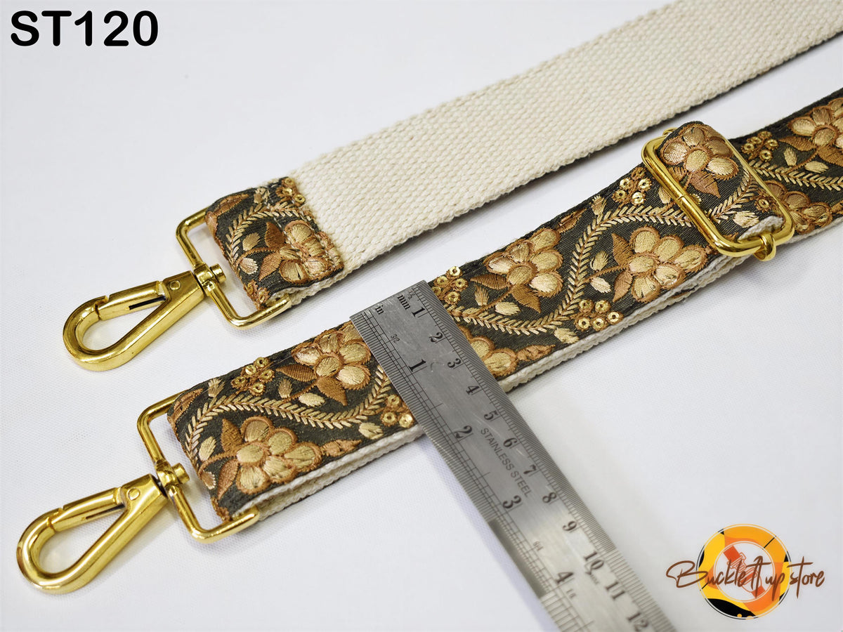 a strap with a floral pattern and two gold metal buckles, with a ruler placed between the strap and the buckle.