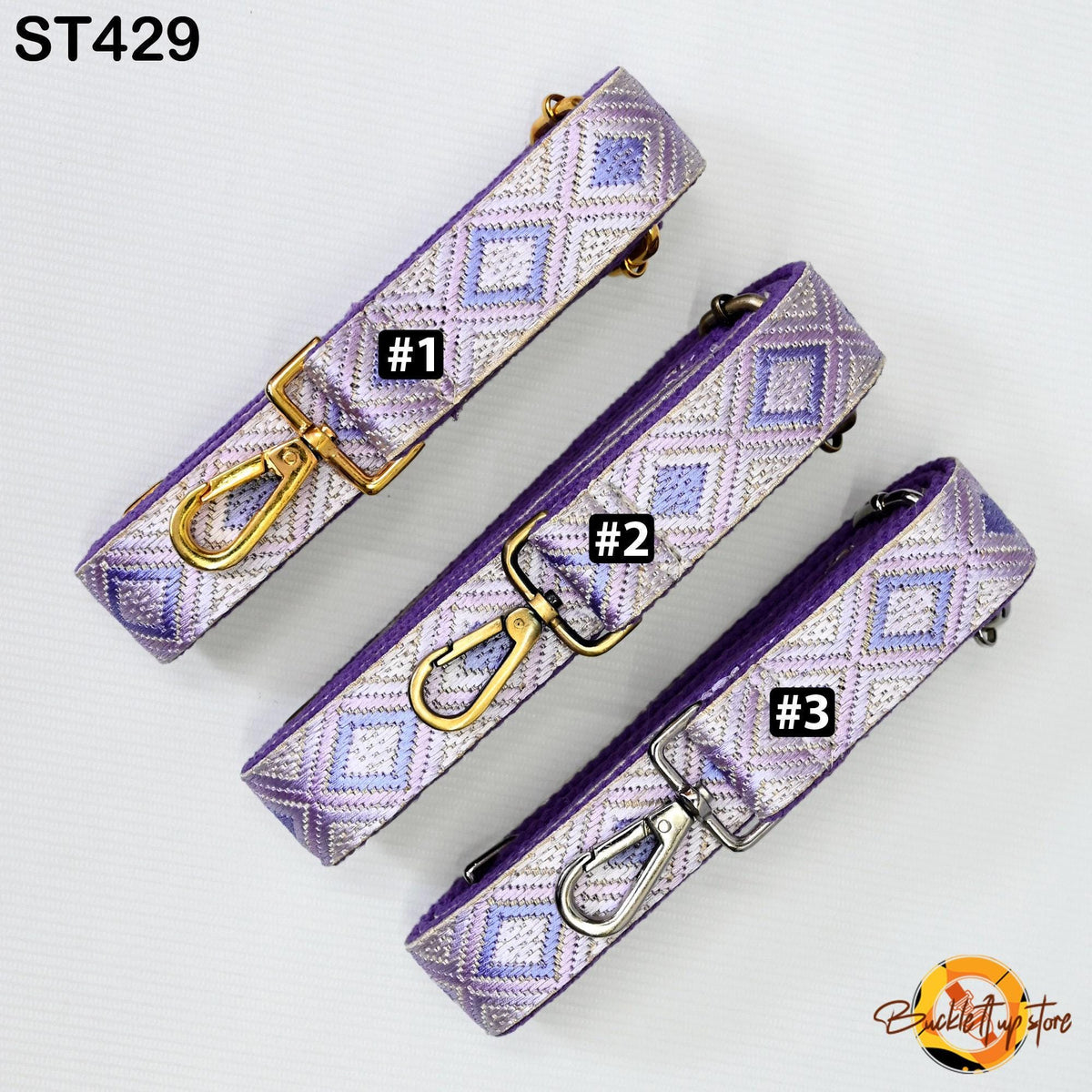 three purple and gold patterned straps with metal hooks, arranged in a row.