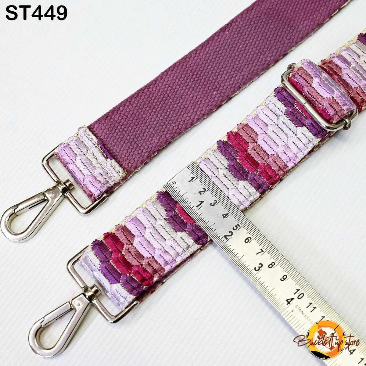 a purple strap with a metal hook attached to it, and a ruler placed next to it, indicating the strap's length.