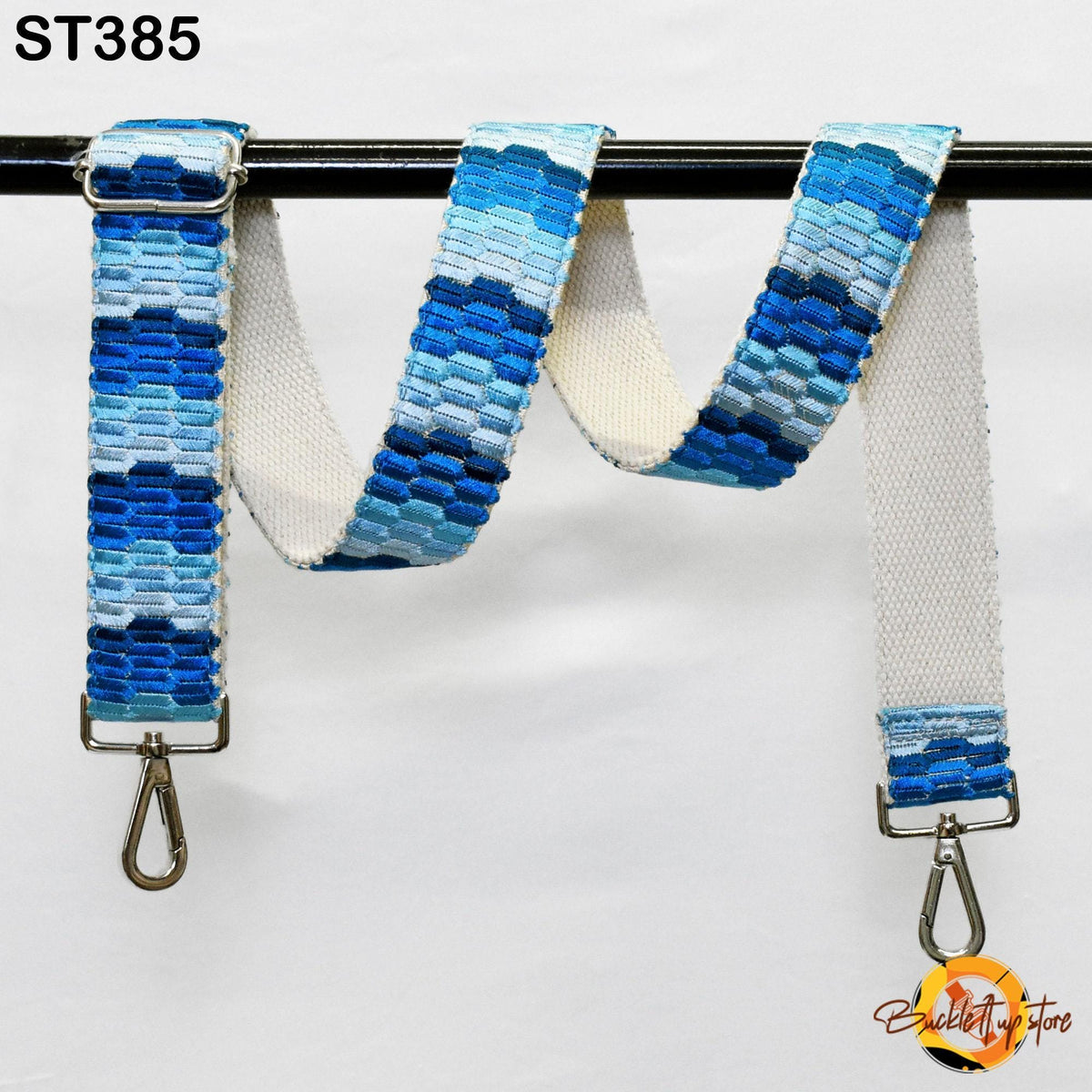 A blue and white patterned strap with metal hooks attached, hanging on a black bar.