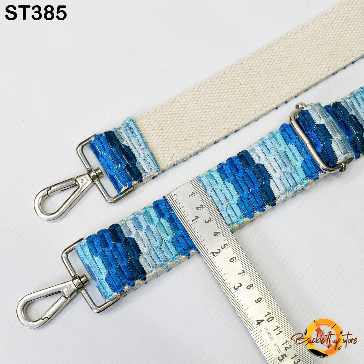 a strap with a metal hook and a ruler placed on it, indicating the strap's size or length.