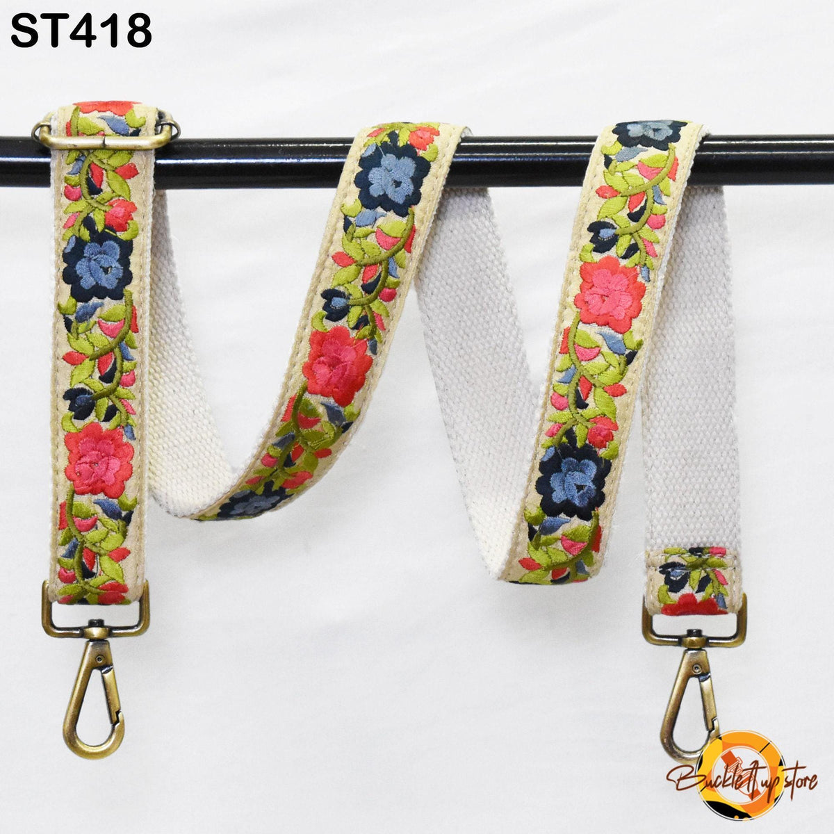 A floral-patterned strap with a metal clasp and hook attached to a black metal bar.