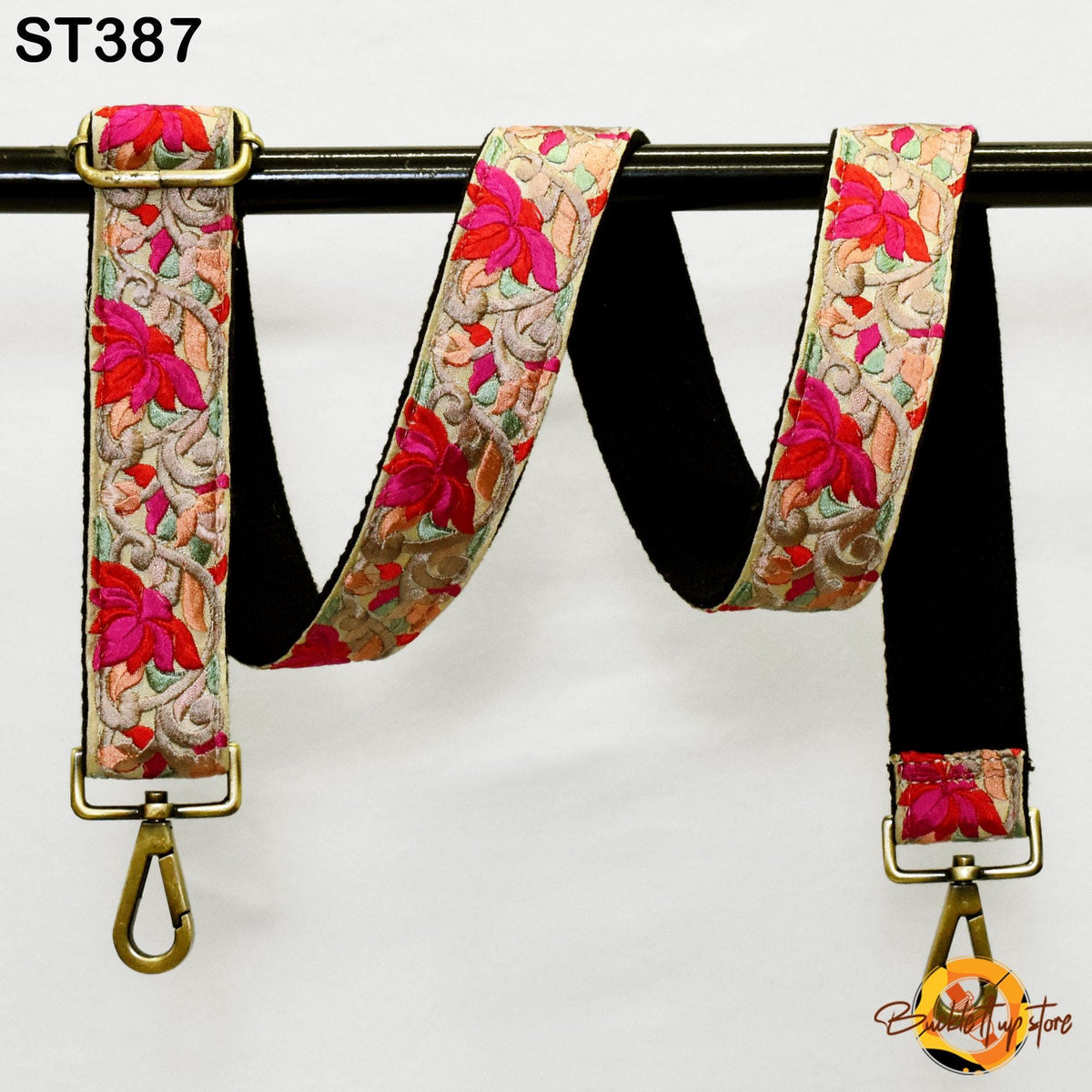 A floral-patterned strap with a black metal buckle, hanging on a black rod.