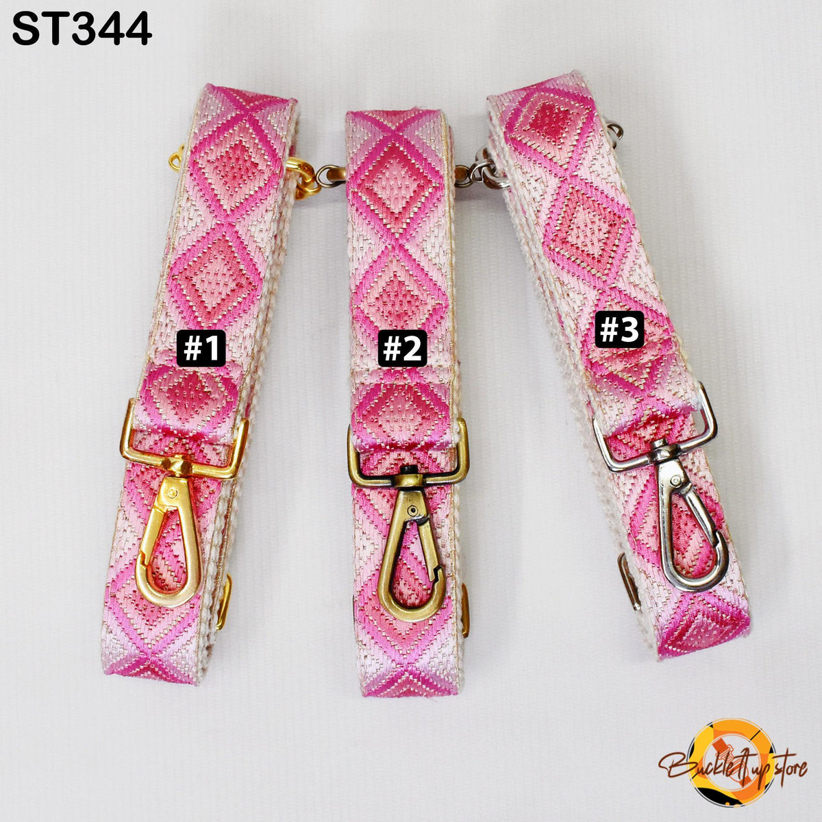 Three pink and white patterned straps with gold buckles, each with a black tag displaying a number.