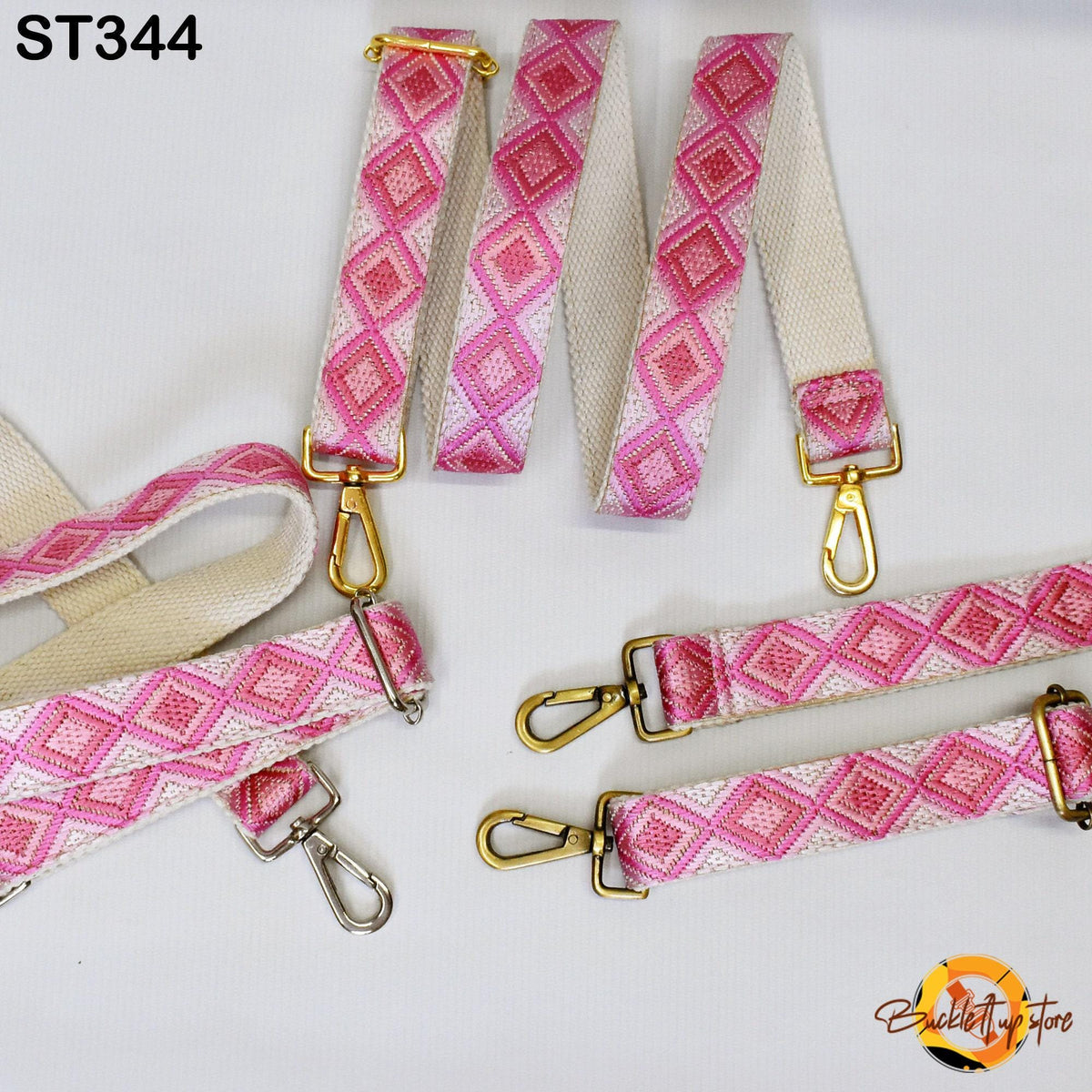 a collection of pink and white patterned straps with gold metal hardware, including buckles and clips, arranged on a white background.