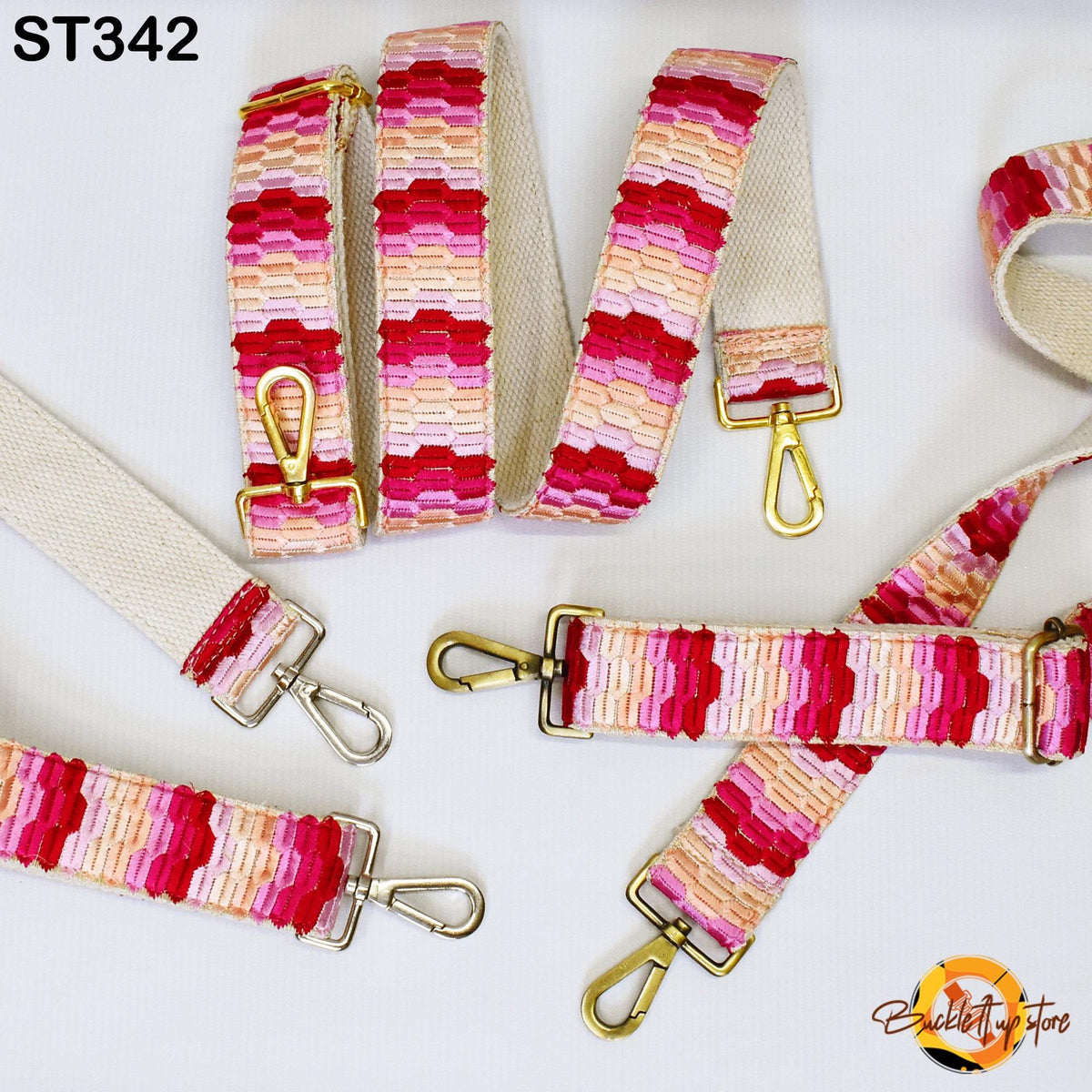 a collection of colorful, patterned straps with gold metal hardware, including a strap with a pink and red striped pattern and another with a geometric design.