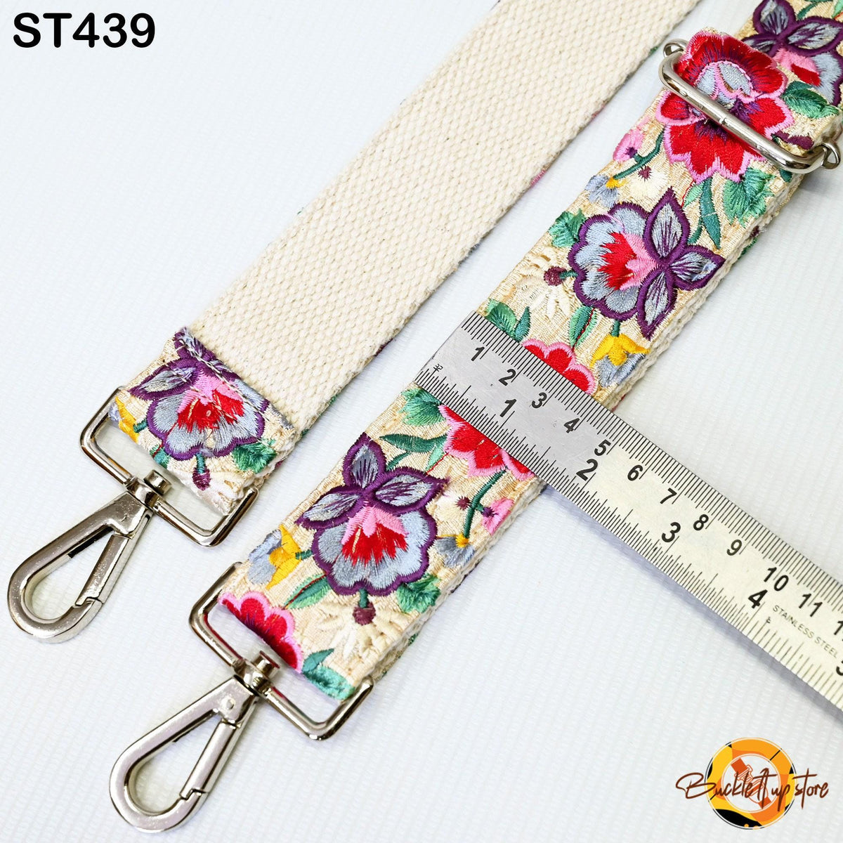 a floral-patterned strap with a metal clasp and a ruler placed on top of it.