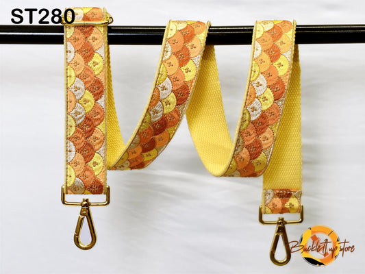 a yellow and orange patterned strap with a metal hook attached to it, hanging on a black bar.