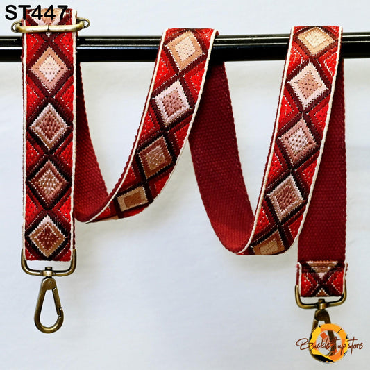 a red and brown patterned strap with a metal clasp, hanging on a black bar.