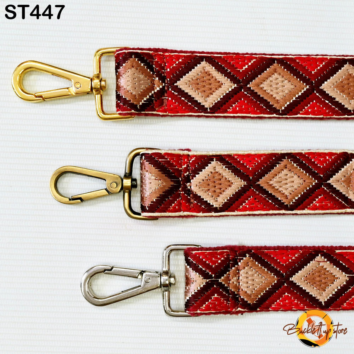 three different straps with a diamond pattern in red, brown, and gold colors. The straps have metal hooks and buckles, and they are arranged in a row on a white background.