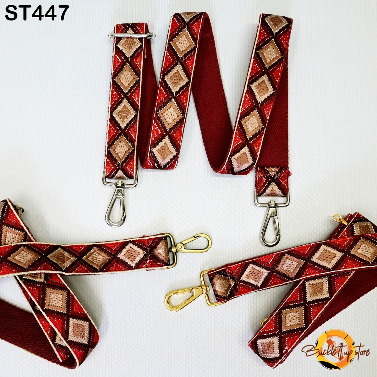 a set of red and gold patterned straps with metal hooks, arranged on a white background.