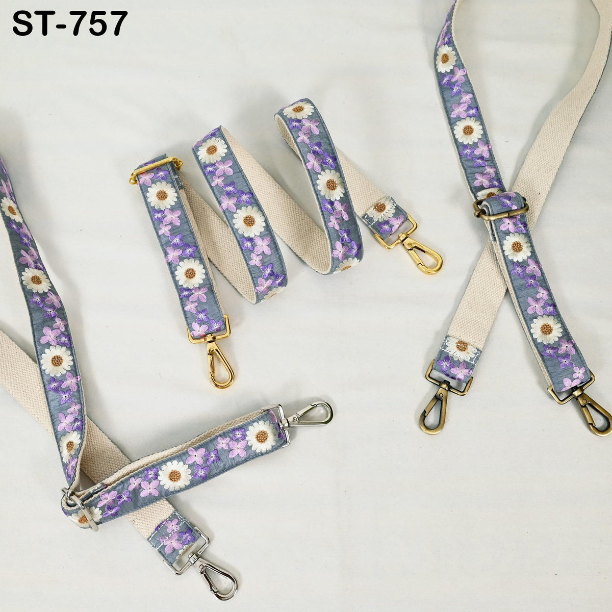 a collection of floral-patterned straps and buckles, including a beige strap with purple and white flowers and a white strap with purple and white flowers. The straps appear to be made of fabric and have metal buckles.