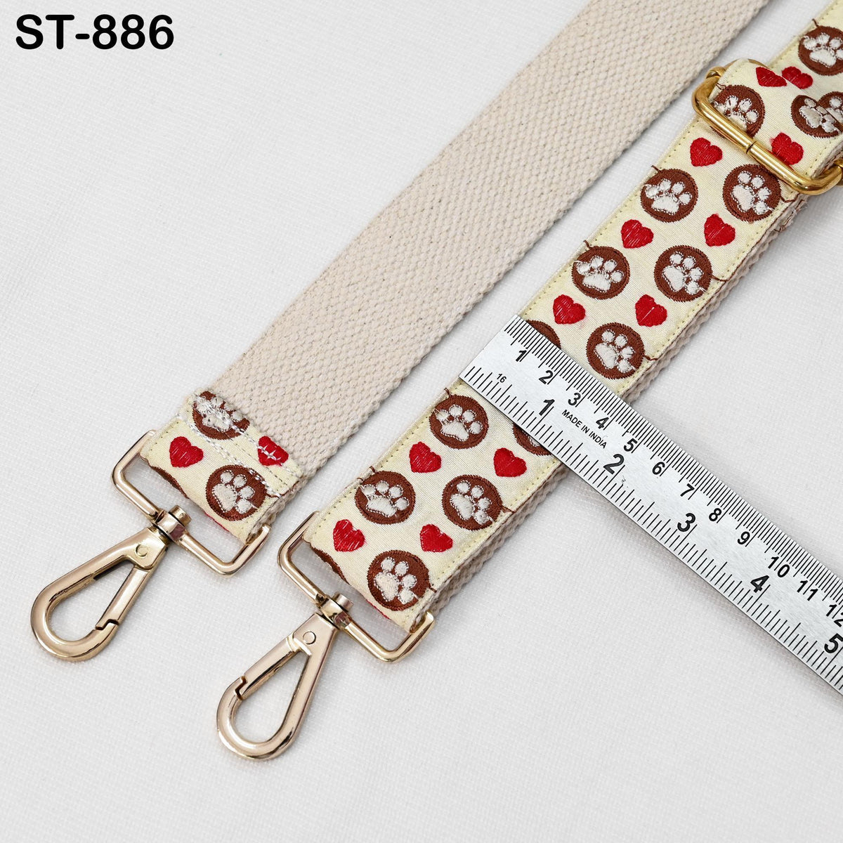 a beige strap with a pattern of hearts and paw prints, and a ruler placed on top of it.