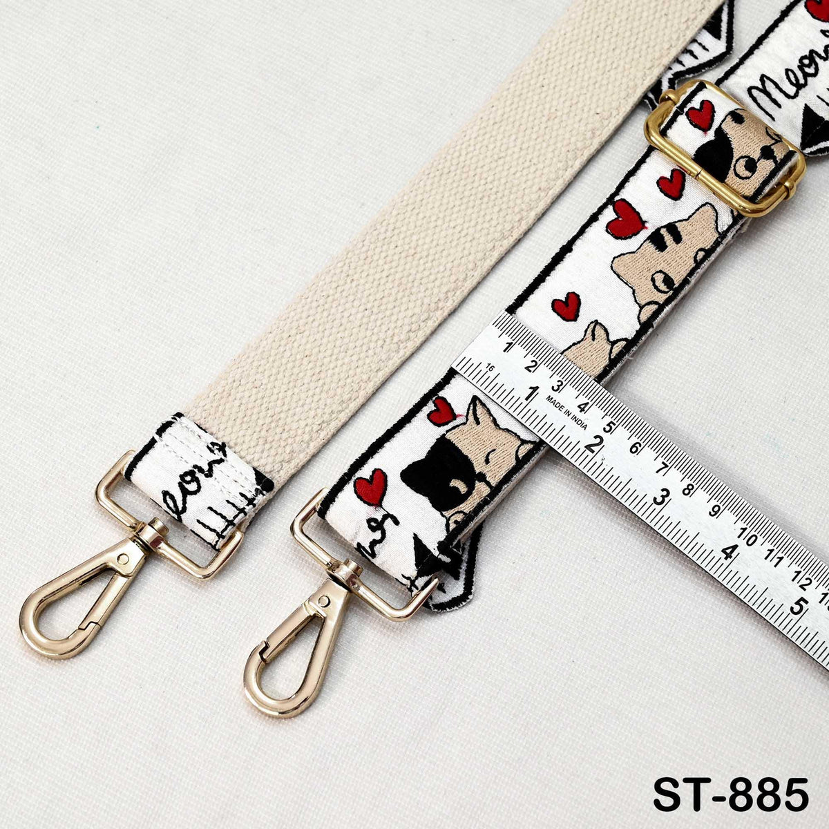 A beige strap with a pattern of hearts and a metal hook attached to it, along with a ruler for size reference.