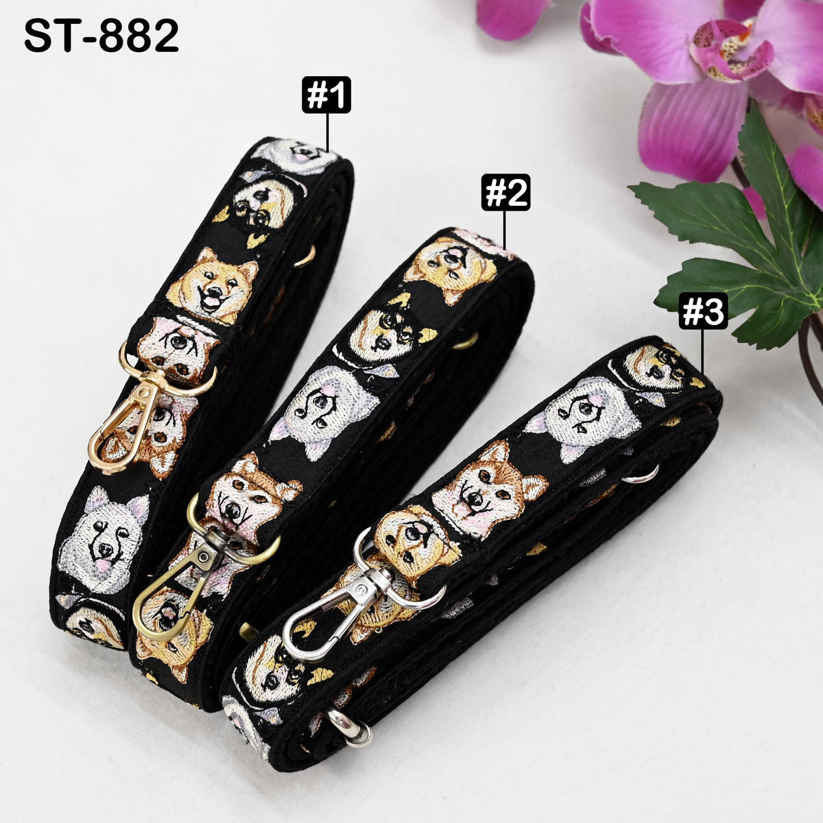 Three colorful dog-themed straps are displayed on a white background, with a pink flower in the background.