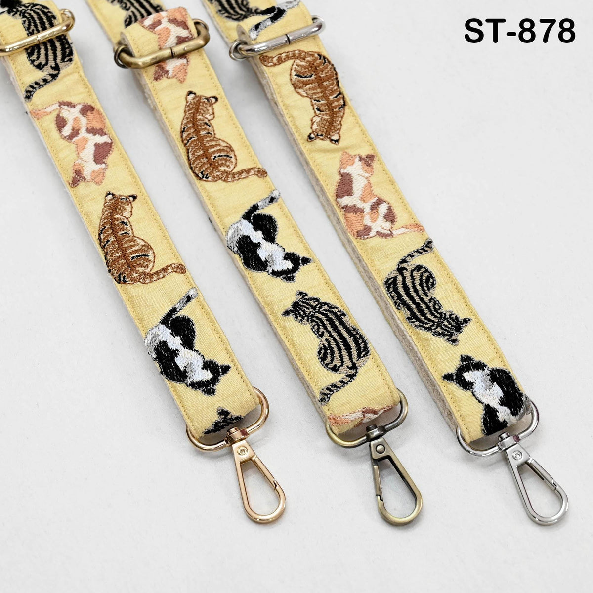 three yellow straps with cat designs, each featuring a metal hook and a metal clasp.