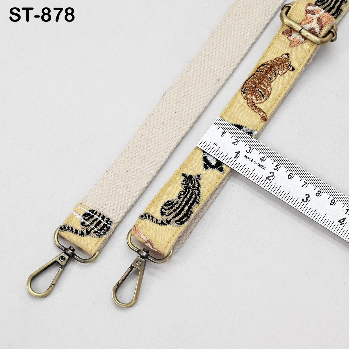 a beige strap with a metal clasp and a ruler placed on top of it, indicating the strap's length.