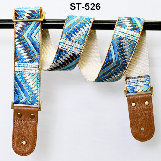 A colorful patterned guitar strap with a leather buckle, hanging on a black bar.