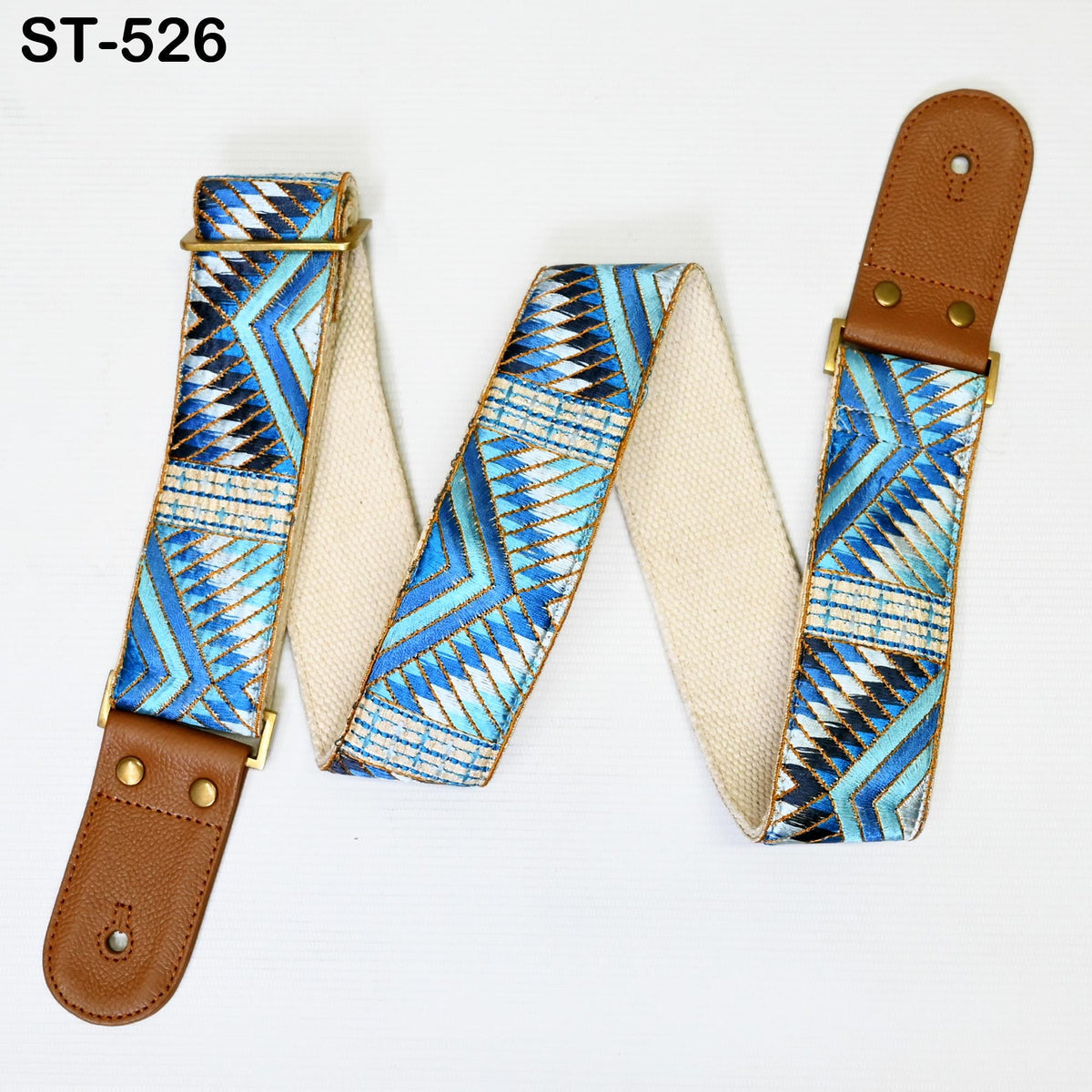 A colorful patterned guitar strap with a brown leather buckle, featuring geometric designs in shades of blue, white, and black.