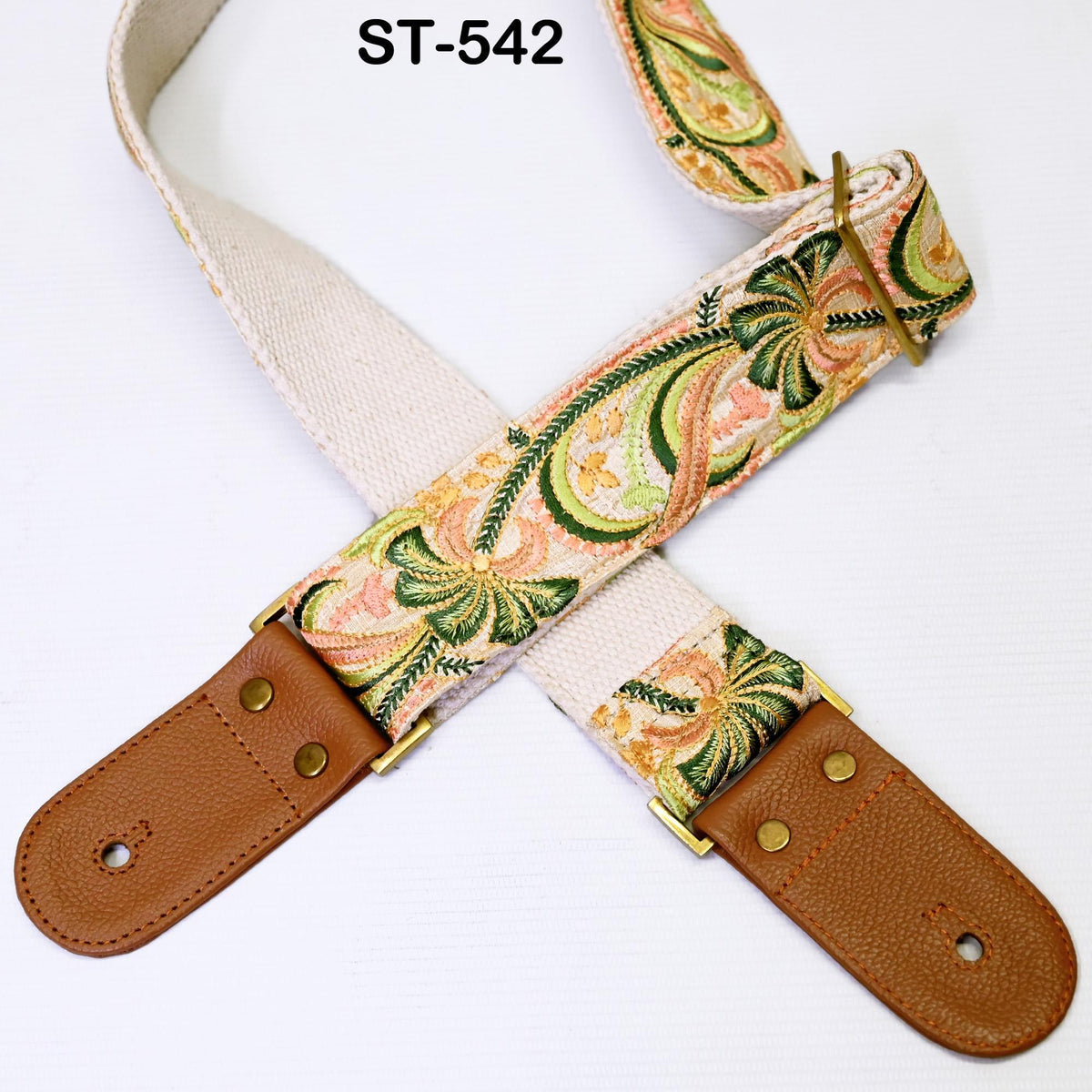 A colorful guitar strap with a floral pattern and a brown leather buckle.