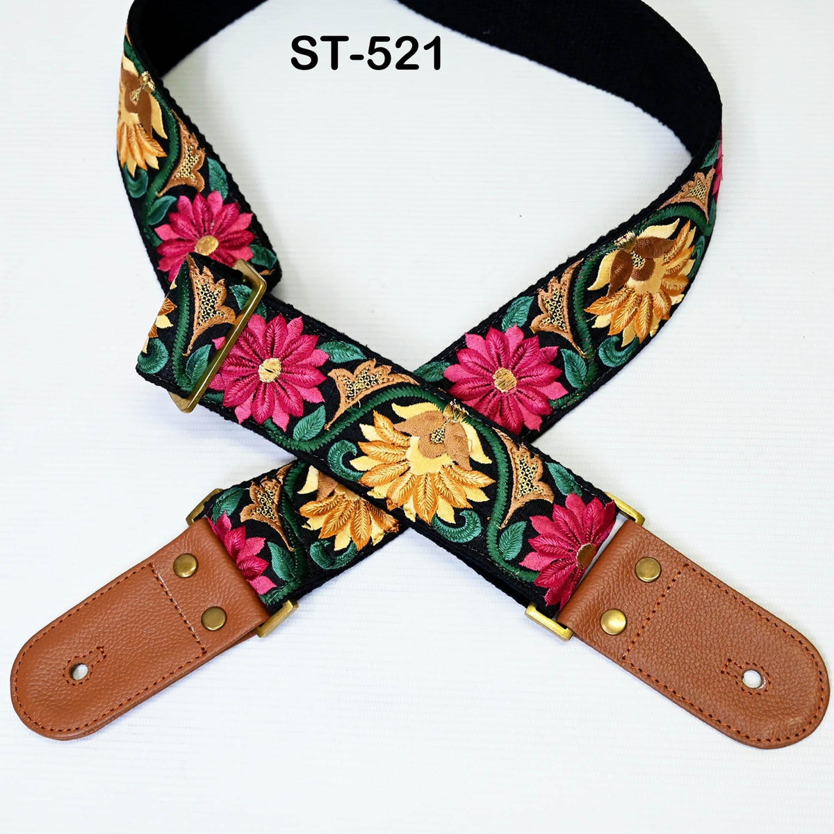 A colorful guitar strap with a floral pattern, featuring a combination of pink, yellow, and green flowers, and a leather-like material.