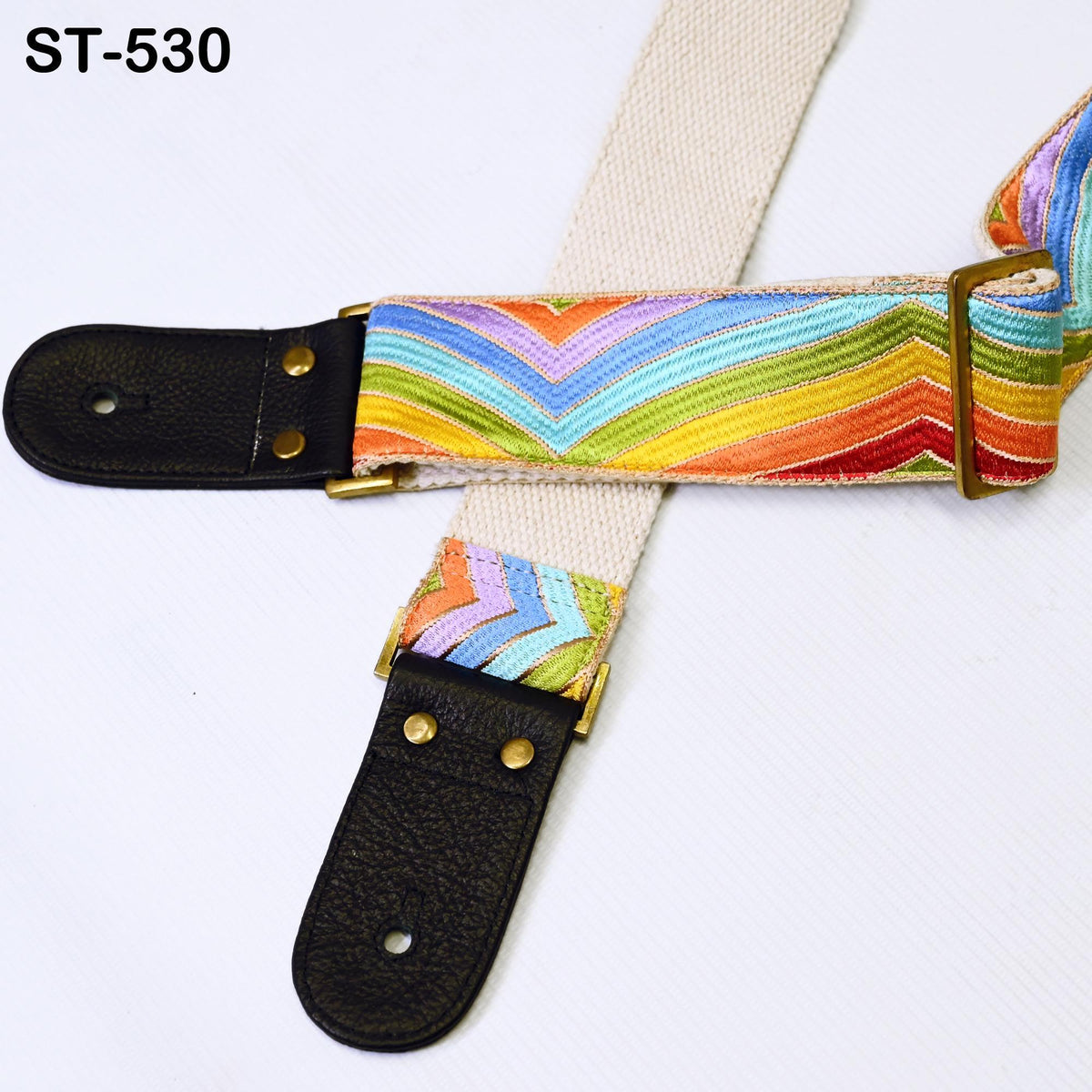 A colorful guitar strap with a black leather buckle and gold hardware.