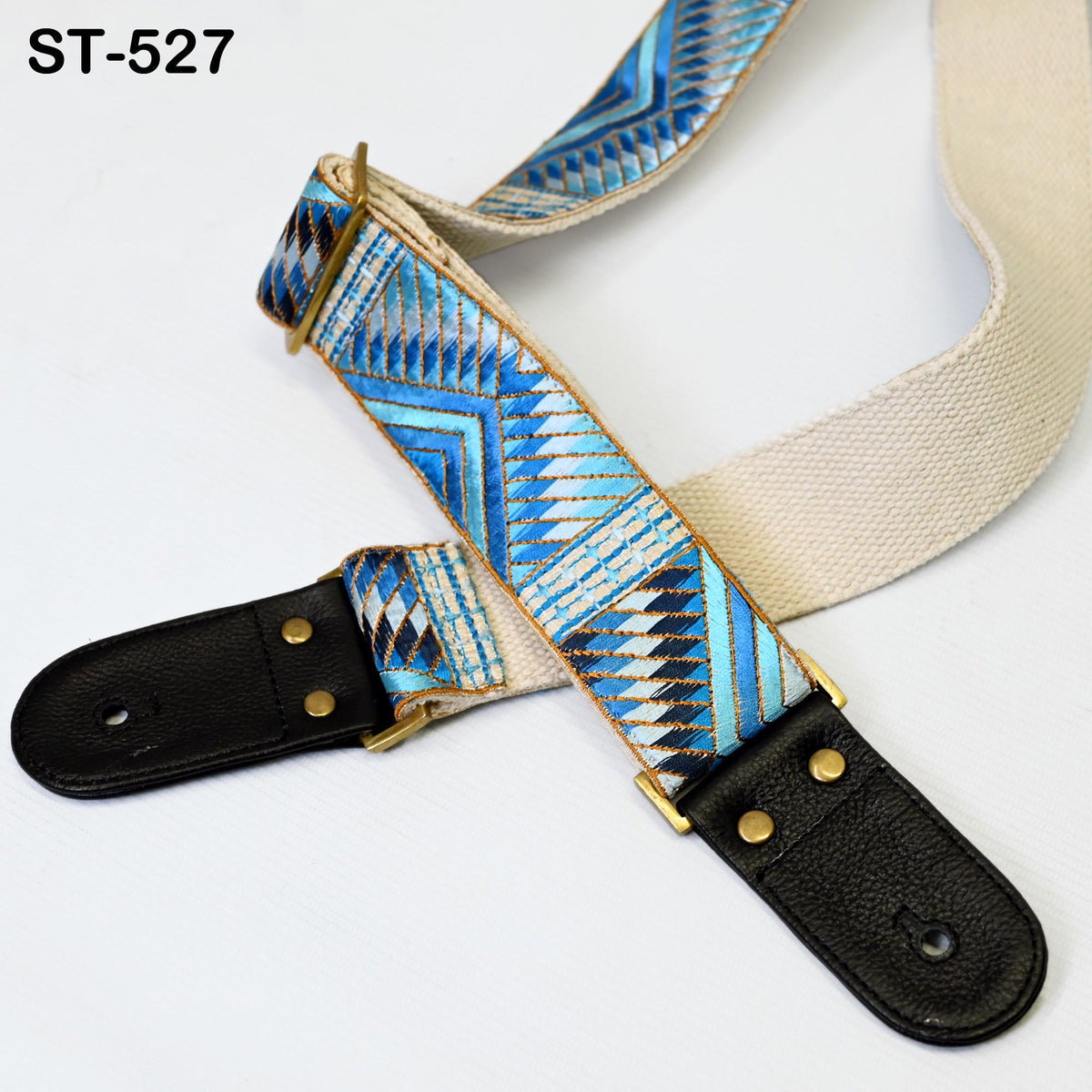 A colorful patterned guitar strap with a black leather buckle, resting on a white surface.
