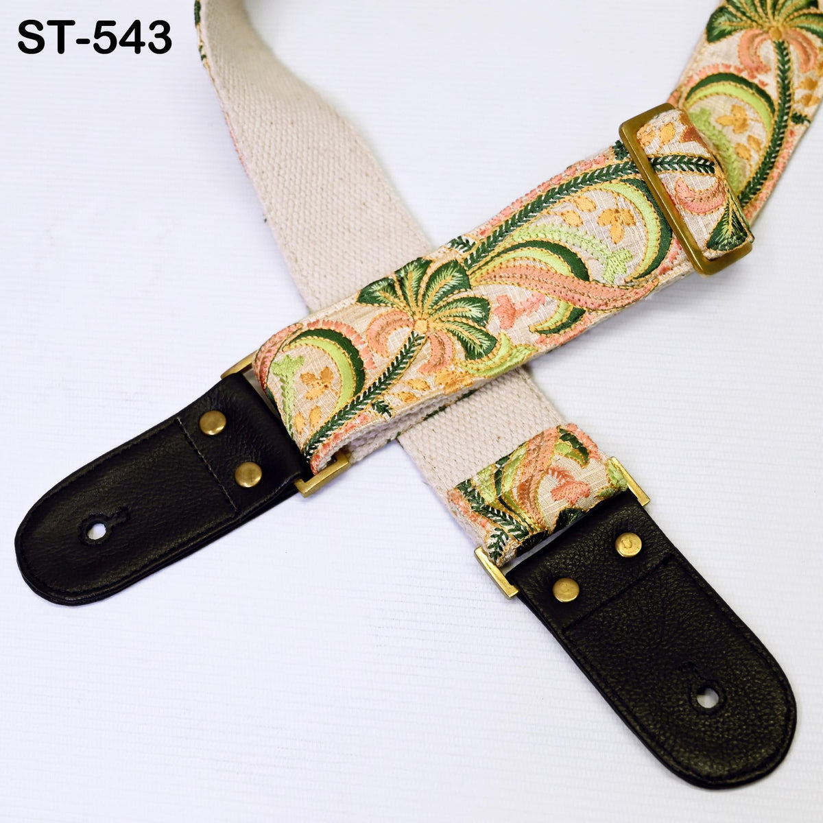 A colorful guitar strap with a floral pattern and a black leather buckle.