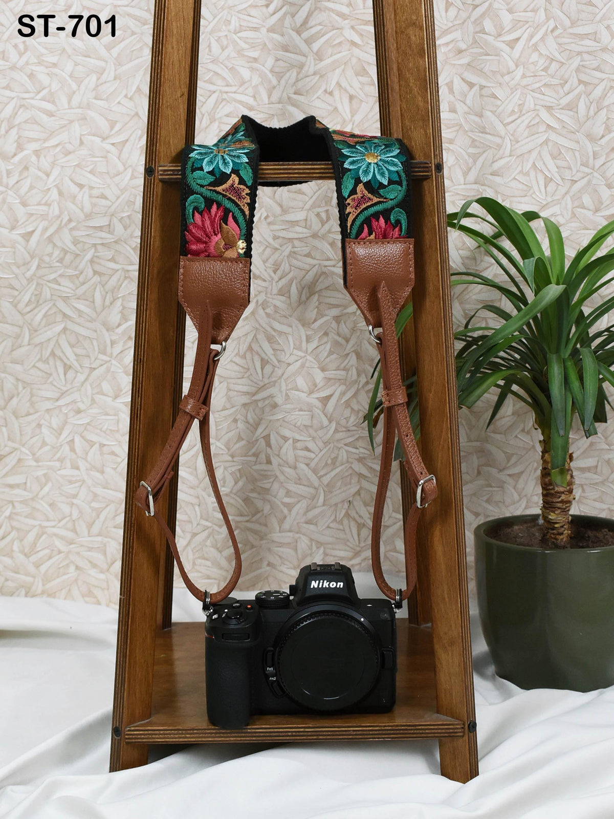 a wooden stand with a black camera on it, and a potted plant is visible in the background.